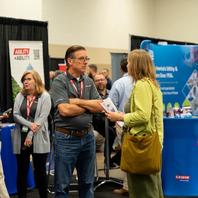 A trade show scene with people engaged in discussions, surrounded by promotional displays and banners. Networking and collaboration are evident.